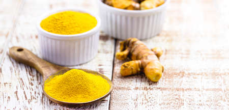 spoonful of powdered turmeric roots, turmeric in wooden bowl on white tableの写真素材