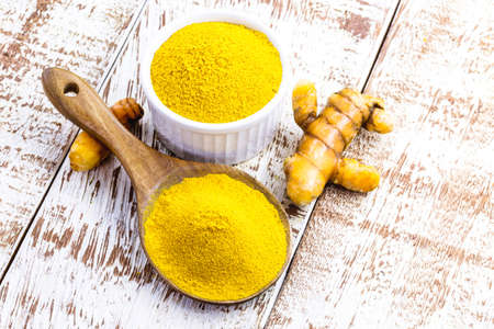 spoonful of powdered turmeric roots, turmeric in wooden bowl on white tableの写真素材
