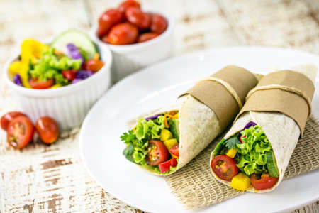 vegan wrap, made of vegetables baked in Indian bread, whole pasta without milk, with vegetables in the backgroundの写真素材