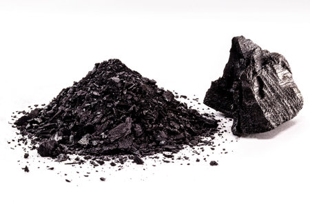 pile of coal dust isolated with piece of charcoal on white background