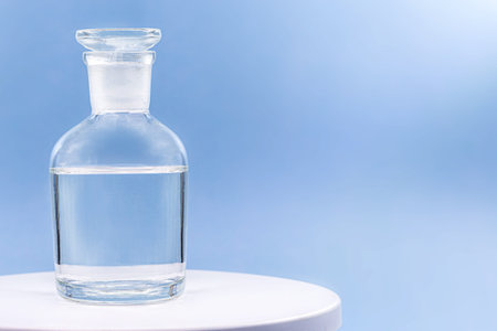 Reagent bottle with glass stopper, blue background, pharmacy or medicine concept, with copy space