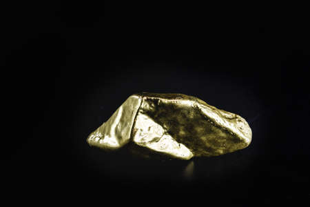 gold nugget on isolated black background, rare stone concept.の写真素材