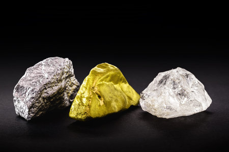 Rough diamond stone with rough gold and silver nuggets on isolated black background.