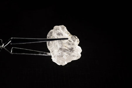 Rough diamond or crystal held by a jeweler's tweezers