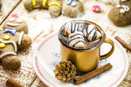 hot chocolate with marshmallows, steam or smoke, homemade Christmas drink, with several gingerbread men on the tableの写真素材