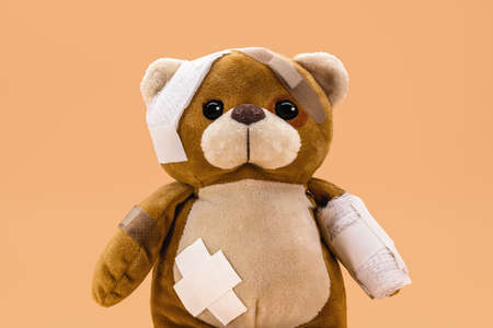 sad injured teddy bear in need of medical care. Conceptual image about violence or child abuseの写真素材