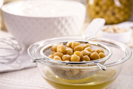 sieve with cooked chickpeas used to make aquafaba, a vegan ingredient that replaces egg whites in...