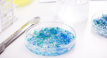 hand of traces of plastic and microplastic in petri dish, analyzed in laboratory, study of...