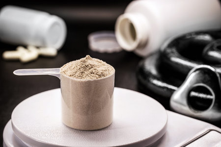 Measuring spoon with creatine or whey, on precision scale, preparing food supplement or casein...