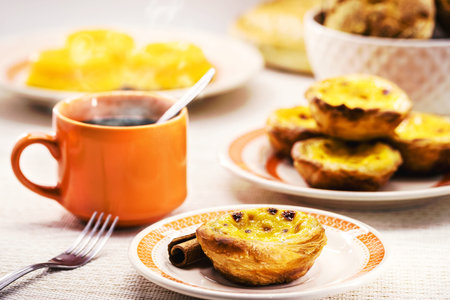 Traditional Portuguese dessert of pastel de nata, and bree de lis and bread in the background,...
