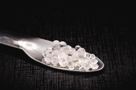 Desiccant or silica gel in white paper packaging and spread on isolated black background, anti...