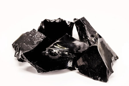 Black Obsidian, black and crystalline ore on isolated white background. Black colored stone, therapeutic, used in meditation.の写真素材