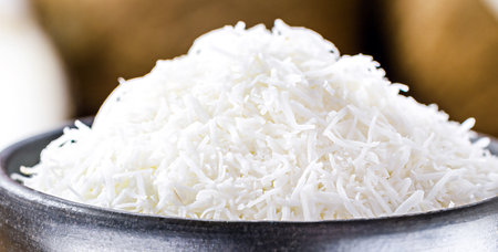 grated coconut, coconut shavings in a clay bowl, with ripe coconuts in the background, on a rustic wooden table , macro photographyの写真素材