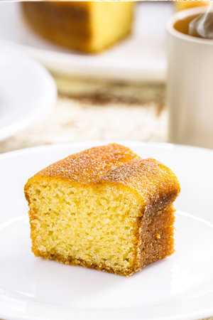small slice of cornmeal cake, typical Brazilian rural cake made with corn flour, with hot coffee in...