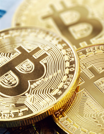 electronic bitcoin coins, with a hundred dollar bill in the background. Devaluation of the Brazilian...