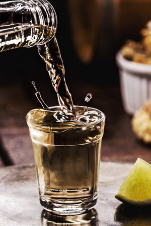 glass of CachaÃ§a, pinga, cana or caninha is the sugar cane brandy, typical drink from Brazil, drops of drink flying, spilling or overflowing, filling the glassの写真素材