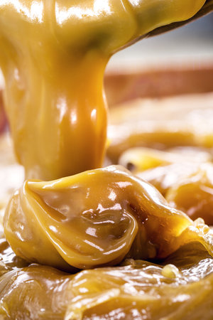 spoon of dulce de leche or homemade vegan pasty milk candy, caramel made with unsweetened coconut milkの写真素材