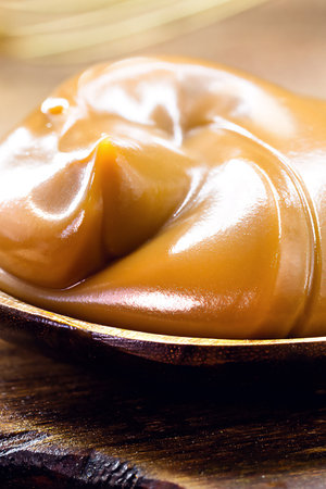 spoon of dulce de leche or homemade vegan pasty milk candy, caramel made with unsweetened coconut milkの写真素材