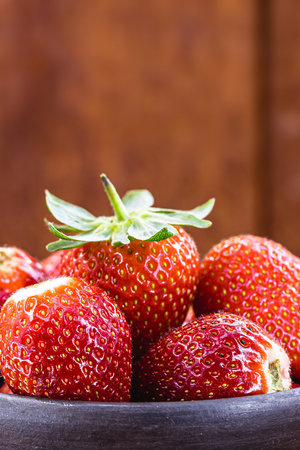 handmade clay pot with Brazilian strawberries of the Albion variety, wooden background, copyspaceの写真素材