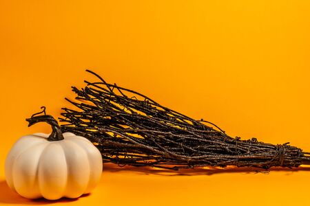 White decorative thanksgiving pumpkin and broom front view on an orange background with room for textの写真素材
