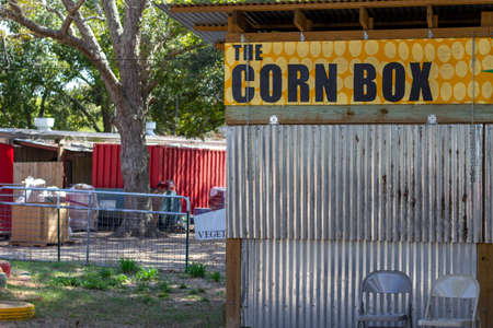 sheet metal building with yellow corn box sign and red barn in backgroundの写真素材