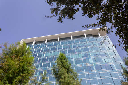 Modern blue glass building from the street up close with blue sky backgroundのeditorial素材