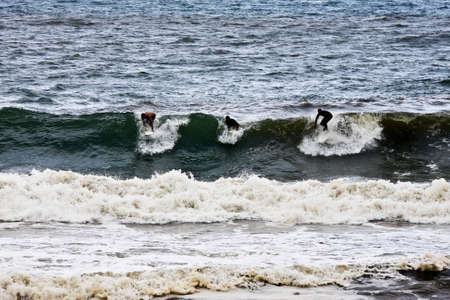 Three surfers catching a waveの写真素材
