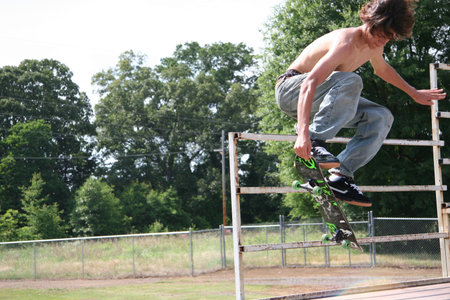 Teen skateboarder flying through air grabbing board.