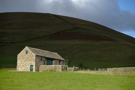 stone farm building in the peak district and bright sun.