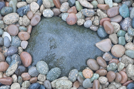 3 - Various sizes of pebbles with a small coating of algae are half submerged in the sea. Water and...