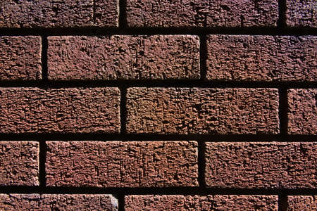 2 - Abstract texture close up of a red brick wall shadows and bright highlights make contrasted image. Fine grain and structure visible. Horizontal.の写真素材