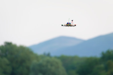 Small home made FPV racing quad copter camera drone flies in front of the malvern hills and trees....