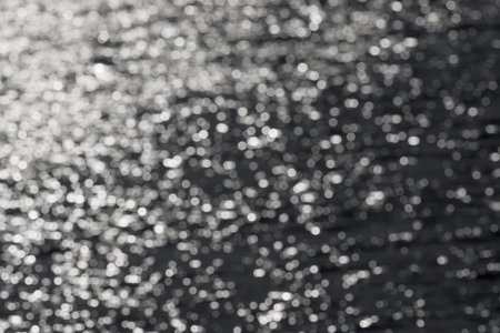 1 - Full frame sparkling out of focus spikes of light, formed from sunlight hitting ripples on a...