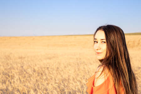 young brunnete women looking at camera on wheat field.の写真素材
