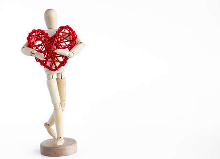 Wooden mannequin holding rattan red heart. White background.の写真素材
