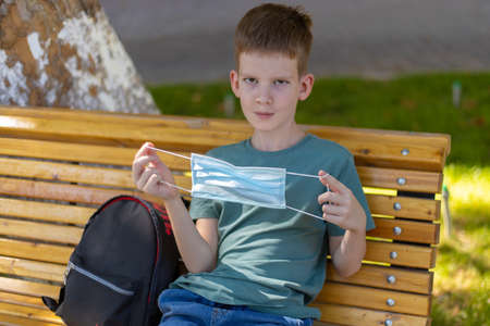 Young caucasian boy looking at the medicine mask then wearing itの写真素材