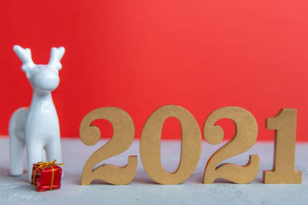 New year red background with shiny golden numbers 2021 and silver pine cone. Minimalistic concept at red paper with hard shadows.の写真素材