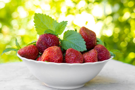 Strawberry with lemon mint leaves in white plate on green backgroundの写真素材
