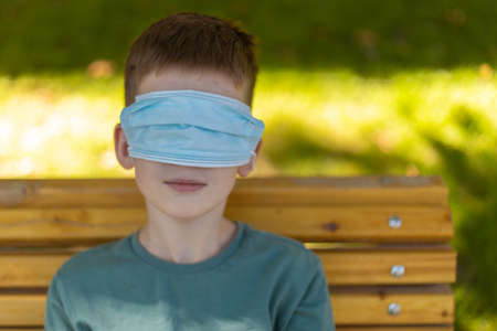 Young caucasian boy wearing wrong medicine mask on eyes. Outdoor.の写真素材