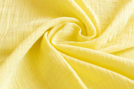 Soft muslin baby blanket background. Cotton clothing and textiles. Natural organic fabrics texture. Light yellow, lemon color. Close up.の写真素材