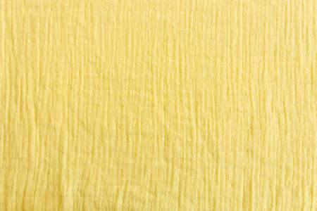 Soft muslin fabrics, baby blanket background. Cotton clothing and textiles. Natural organic fabrics texture. Light yellow, , lemon color. Close up. Top viewの写真素材