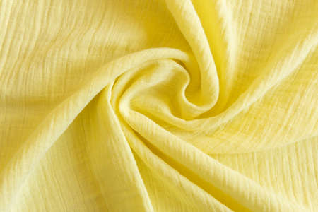 Soft muslin baby blanket background. Cotton clothing and textiles. Natural organic fabrics texture. Light yellow, lemon color. Close up.の写真素材