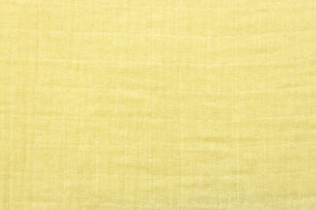 Soft muslin fabrics, baby blanket background. Cotton clothing and textiles. Natural organic fabrics texture. Light yellow, , lemon color. Close up. Top viewの写真素材