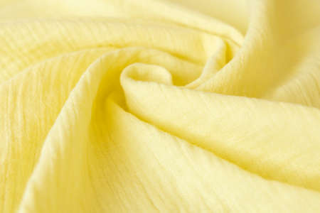 Soft muslin baby blanket background. Cotton clothing and textiles. Natural organic fabrics texture. Light yellow, lemon color. Close up.の写真素材