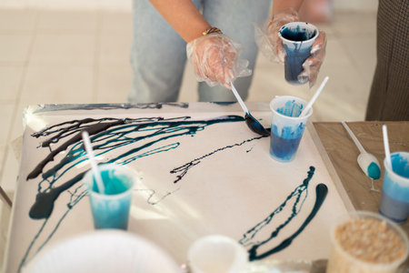Epoxy resin different blue color in cup for abstract art. Woman hands process of making accessory from resin.Mixing colorful of resin chemical in plastic cupの写真素材