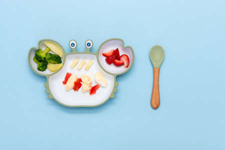 Baby Led weaning, blw. First baby food. Silicon plate with mixed vegetable. Healthy nutrition for kid, self feeding. Soft eco plastic tableware.の写真素材