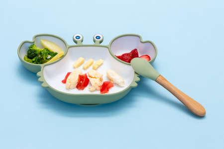 Baby Led weaning, blw. First baby food. Silicon plate with mixed vegetable. Healthy nutrition for kid, self feeding. Soft eco plastic tableware.の写真素材