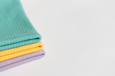 Stack folded purple, yellow, green baby cotton clothing on white background isolation. Copy space. For advertising, commercial,mock up.の写真素材