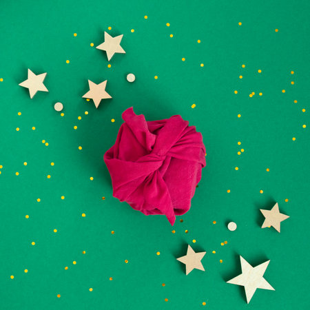 Paper free gift wrapping technique Furoshiki. Viva magenta fabric on green background. Flat lay, present box, top view. Christmas, valentines, new year concept.の写真素材