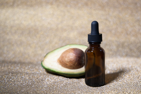 Avocado oil. Essential oil in glass bottle on shiny gold background. Avocado for healthy skin and hair. Cosmetics ingridient. Space for text.の写真素材